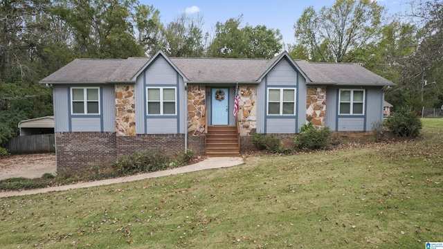 ranch-style home with a shingled roof, a front yard, stone siding, and brick siding