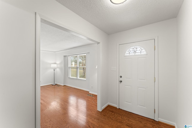 entrance foyer featuring visible vents, a textured ceiling, baseboards, and wood finished floors