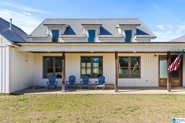 back of property with metal roof, a lawn, and a patio area