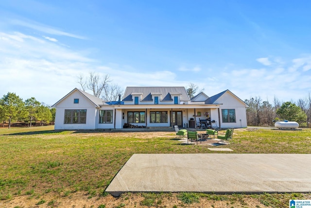 rear view of house with a lawn, metal roof, and a patio