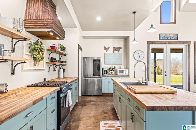 kitchen featuring open shelves, a sink, butcher block countertops, appliances with stainless steel finishes, and blue cabinets