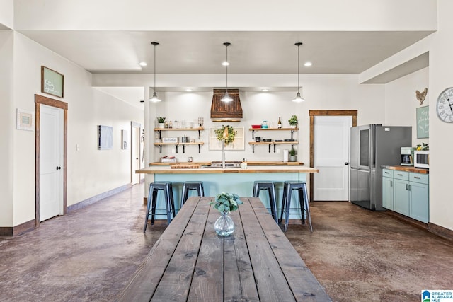 kitchen with finished concrete floors, open shelves, freestanding refrigerator, and butcher block counters