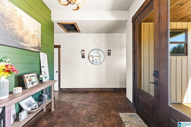 foyer entrance featuring baseboards, concrete floors, and wood walls