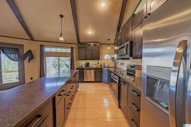 kitchen featuring appliances with stainless steel finishes, beam ceiling, dark stone countertops, and decorative backsplash