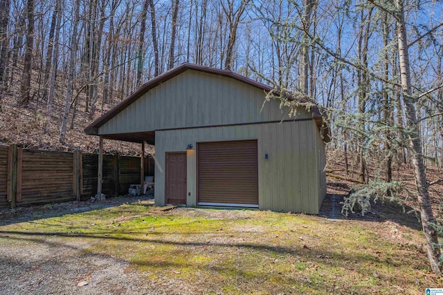 detached garage featuring driveway and fence