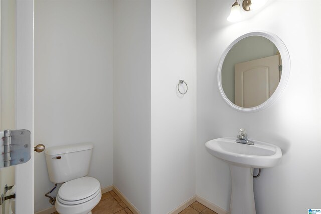 half bathroom featuring toilet, tile patterned flooring, and baseboards