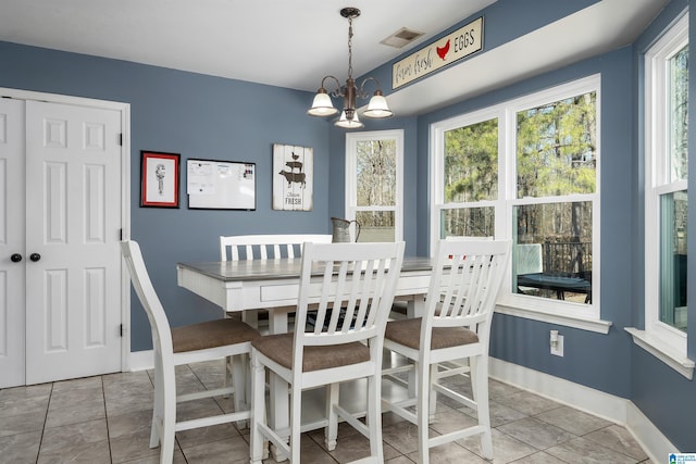 tiled dining area featuring baseboards, visible vents, and a notable chandelier