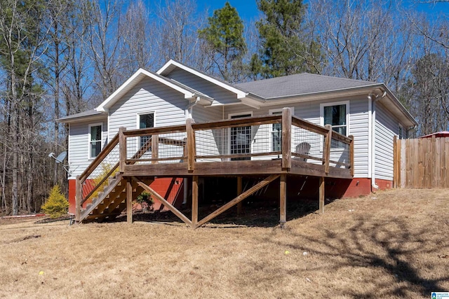 view of front of home featuring stairway, roof with shingles, fence, a deck, and a front lawn