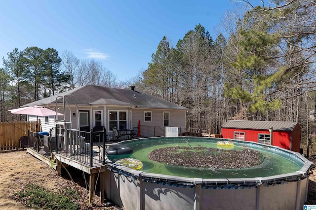 rear view of house featuring fence, an outdoor structure, a fenced in pool, and a wooden deck