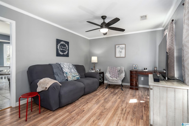 living area featuring visible vents, ornamental molding, a ceiling fan, wood finished floors, and baseboards