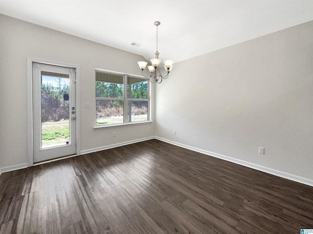 empty room with dark wood-style floors, baseboards, visible vents, and a notable chandelier