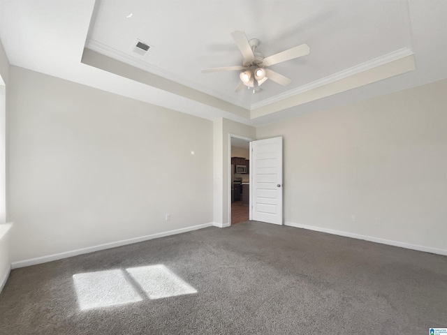 unfurnished bedroom featuring crown molding, a raised ceiling, visible vents, dark carpet, and baseboards