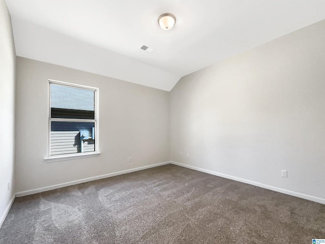 carpeted empty room with lofted ceiling, baseboards, and visible vents