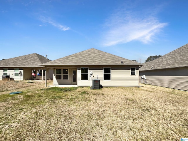 rear view of property with a shingled roof, a yard, and central air condition unit