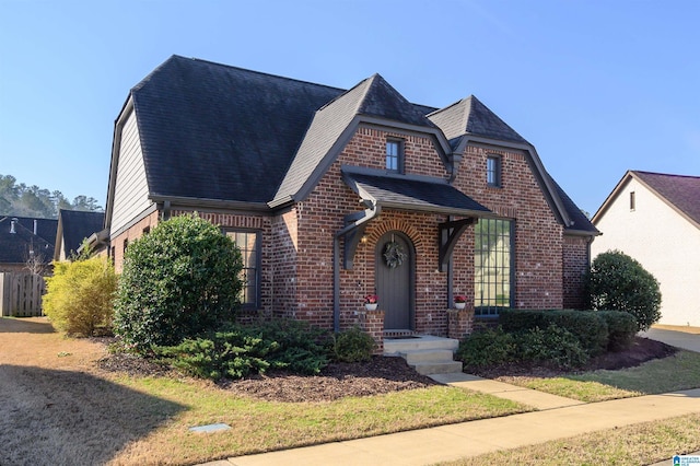 view of front of house with brick siding and roof with shingles