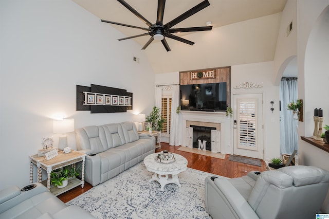 living area with visible vents, high vaulted ceiling, a fireplace, arched walkways, and ceiling fan