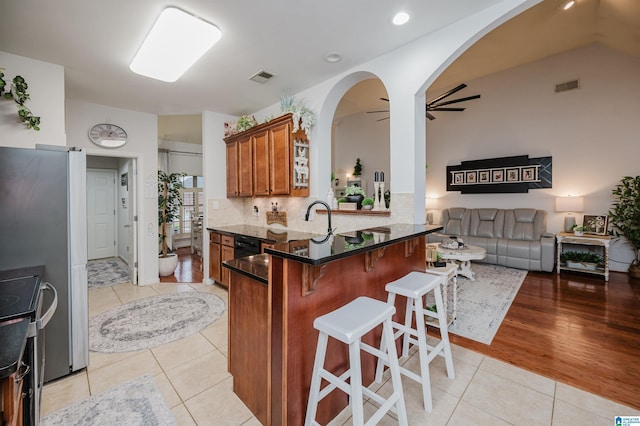 kitchen featuring electric stove, visible vents, brown cabinets, and arched walkways