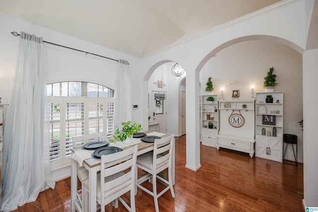 dining space with crown molding, wood finished floors, and arched walkways