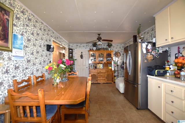 dining space with a ceiling fan and wallpapered walls