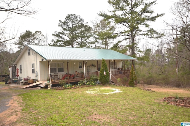 view of front of house featuring covered porch, metal roof, and a front lawn