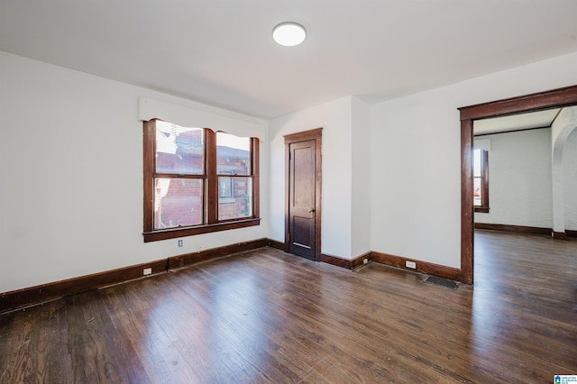 empty room featuring wood finished floors, visible vents, and baseboards