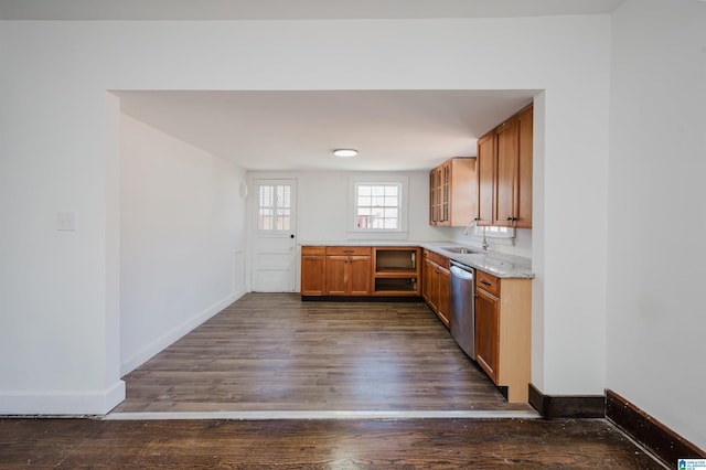 kitchen featuring dark wood finished floors, brown cabinets, dishwasher, and baseboards