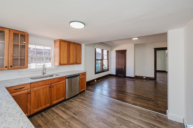 kitchen with stainless steel dishwasher, a sink, a wealth of natural light, and brown cabinets