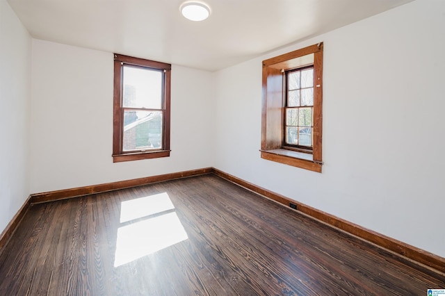 unfurnished room with dark wood-style floors and baseboards