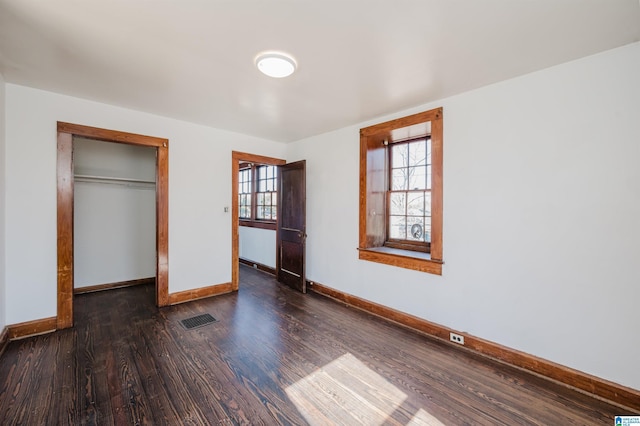 unfurnished bedroom featuring a closet, wood finished floors, visible vents, and baseboards