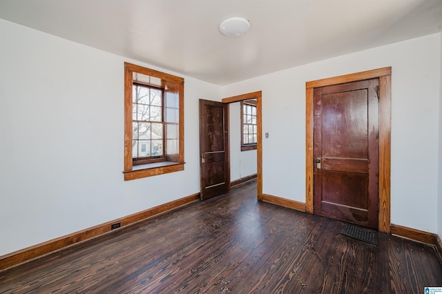 unfurnished room featuring visible vents, baseboards, and wood finished floors