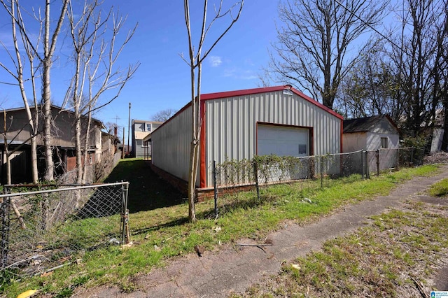 exterior space featuring a detached garage, fence, and an outbuilding