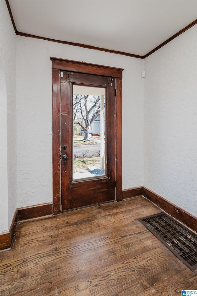 foyer entrance with crown molding, visible vents, hardwood / wood-style floors, and a textured wall