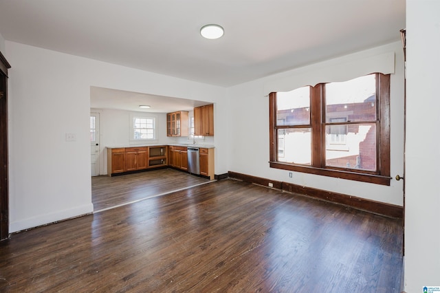 unfurnished living room featuring a sink, dark wood finished floors, and baseboards