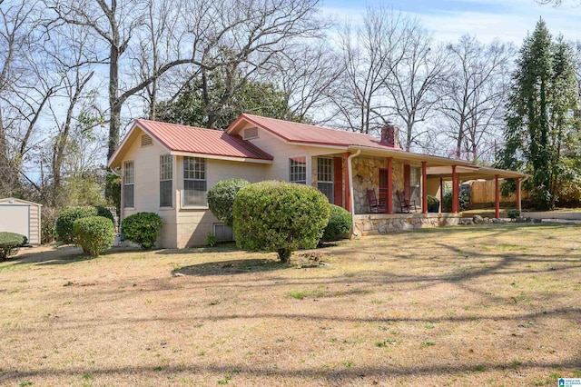 view of front of home featuring metal roof, an outdoor structure, stone siding, a chimney, and a front yard