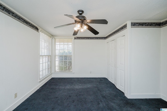 unfurnished bedroom featuring ornamental molding, dark colored carpet, a closet, and baseboards