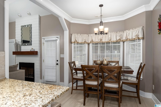 dining area featuring a notable chandelier, a fireplace, visible vents, baseboards, and ornamental molding