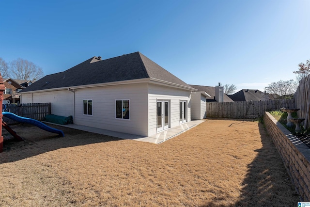 rear view of property with a shingled roof, a patio area, a fenced backyard, and french doors