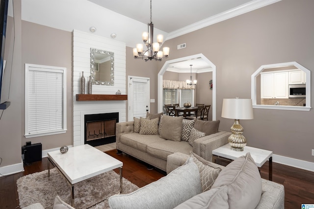 living room featuring arched walkways, a notable chandelier, a fireplace, wood finished floors, and baseboards