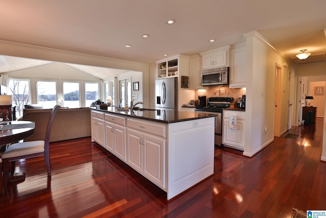 kitchen with a center island with sink, dark wood finished floors, white cabinets, appliances with stainless steel finishes, and backsplash