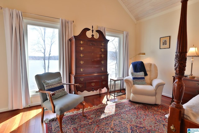 living area with crown molding, vaulted ceiling, and wood finished floors