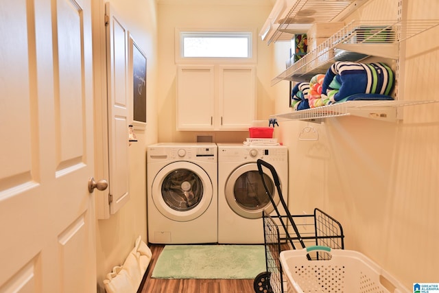 washroom featuring cabinet space, washing machine and clothes dryer, and wood finished floors