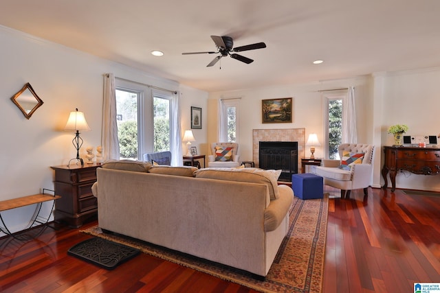 living area with dark wood-style floors, a ceiling fan, a tiled fireplace, and recessed lighting