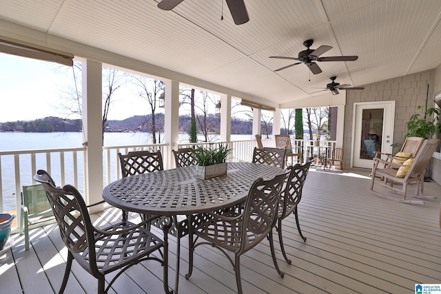 wooden deck with a water view, ceiling fan, and outdoor dining space