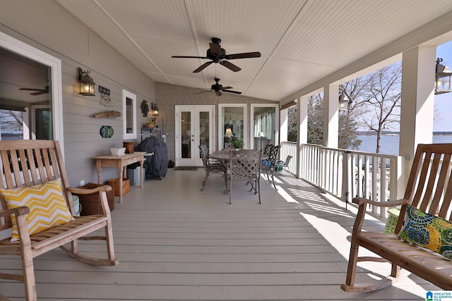 wooden deck with a water view, grilling area, a ceiling fan, and french doors