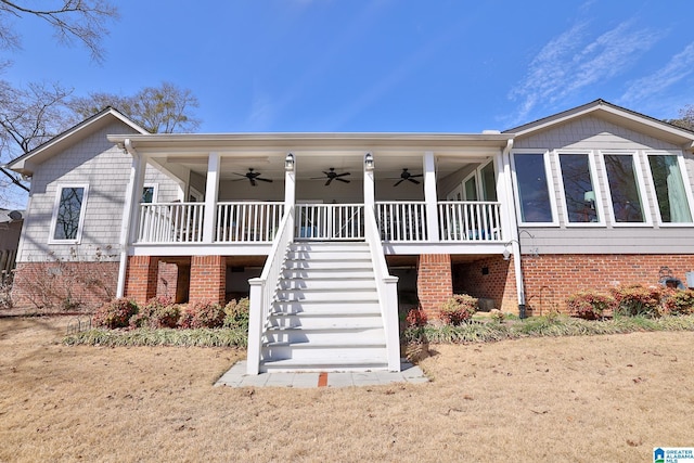 view of front of home featuring stairs, ceiling fan, and brick siding