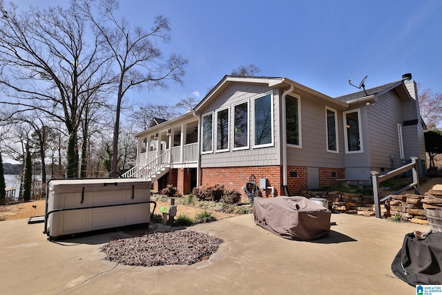 view of side of property featuring stairway, a chimney, and a hot tub