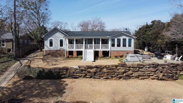 back of property with a hot tub, an outdoor fire pit, a patio area, fence, and stairs