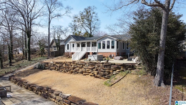 back of house featuring a sunroom, a patio area, brick siding, and stairs