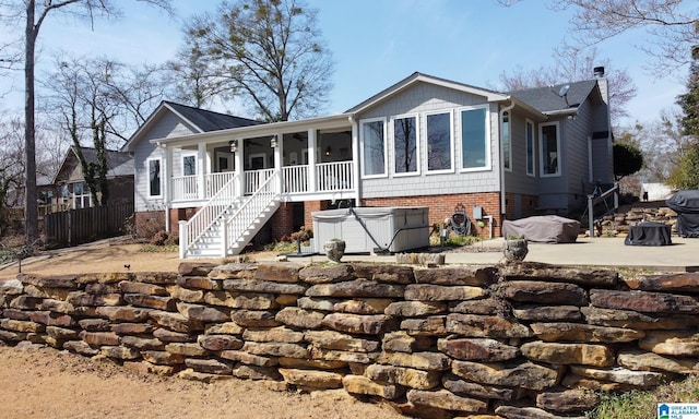 view of front of property featuring fence, a ceiling fan, stairway, a chimney, and a hot tub