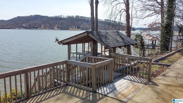 wooden terrace featuring a forest view and a water view